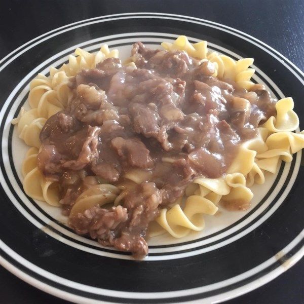 pasta with meat and sauce is on a black and white plate, ready to be eaten