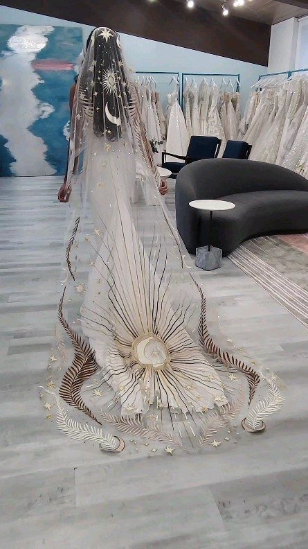 a woman is walking down the runway in a wedding dress with an elaborate veil on her head