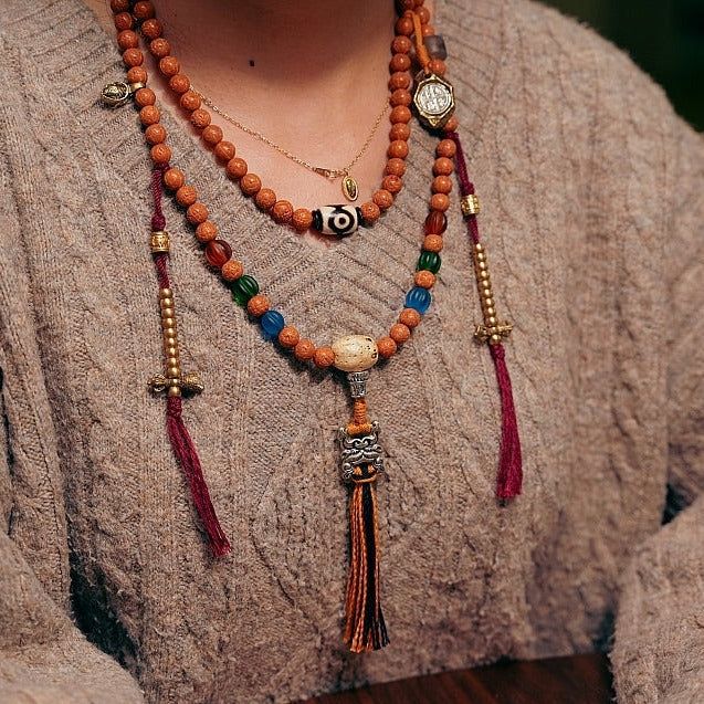 Experience the wisdom of Yama principles and tap into the transformative energy of 108 Bodhi Seed and Tibetan Agate Mala Beads. Explore ancient teachings and wear the lovely Tibetan Agate beads to find inner peace and harmony on your spiritual path. · Material: Bodhi Seed· Yama Pendant: White Copper· Tibetan Astrology Pendant: Brass· Thread: Cotton· Size: 8mm· Process: Handmade (Up to three days) Five- Eyed Bodhi Seed Tibetan Agate Yak Horn Lamp work glass additions The Bell and Dorje Amulets ar Luxury Traditional Beads, Tibetan Jewelry Boho, Holistic Necklaces With Wooden Beads For Festivals, Holistic Festival Necklaces With Wooden Beads, Spiritual Wooden Beads Mala For Festival, Adjustable Amulet Mala For Rituals, Holistic Mala With 108 Beads For Festival, Bohemian Wooden Beads Mala For Festival, Bohemian Festival Mala With Wooden Beads