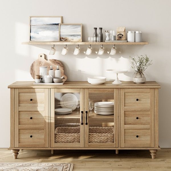 a wooden cabinet with plates and cups on it in a room that has white walls