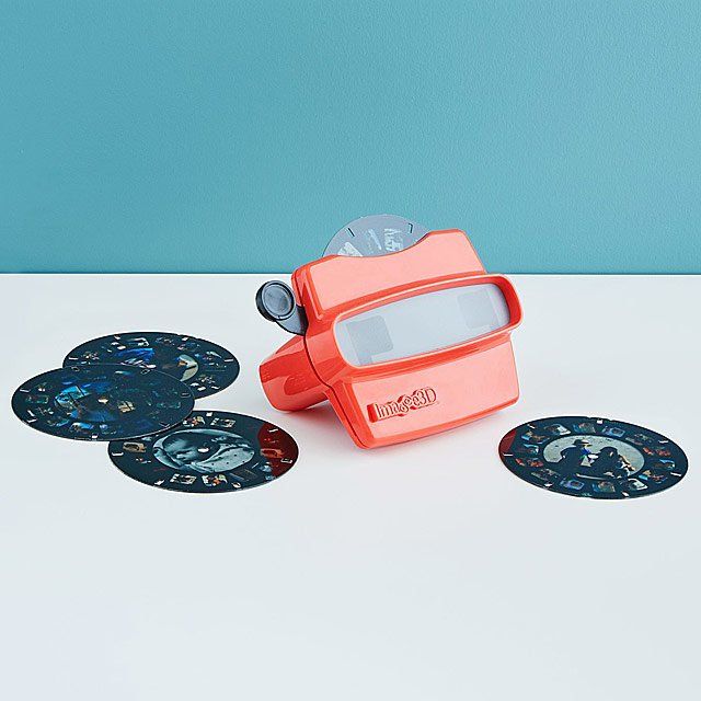 a red object sitting on top of a white table next to some coasters and a blue wall