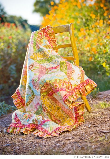 an old chair covered with a colorful blanket in the middle of a flowery field