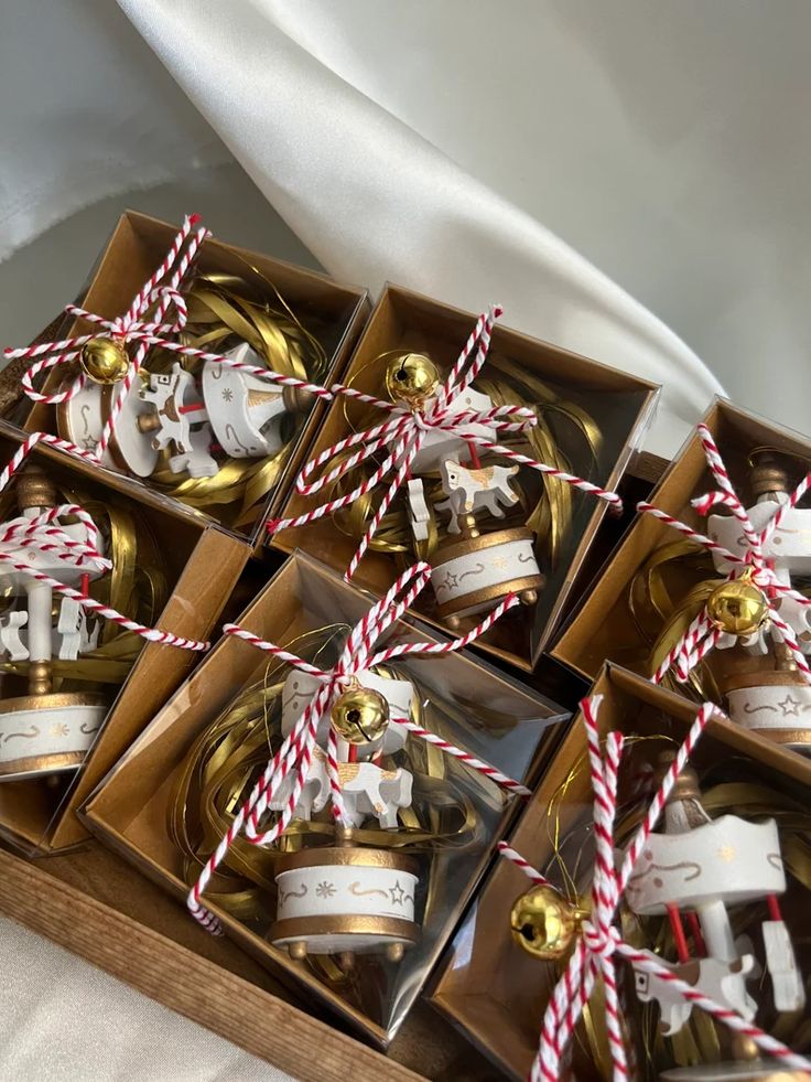 twelve christmas ornaments in boxes tied with red and white twine