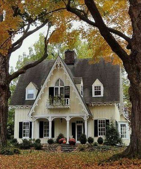 a white house surrounded by trees and leaves