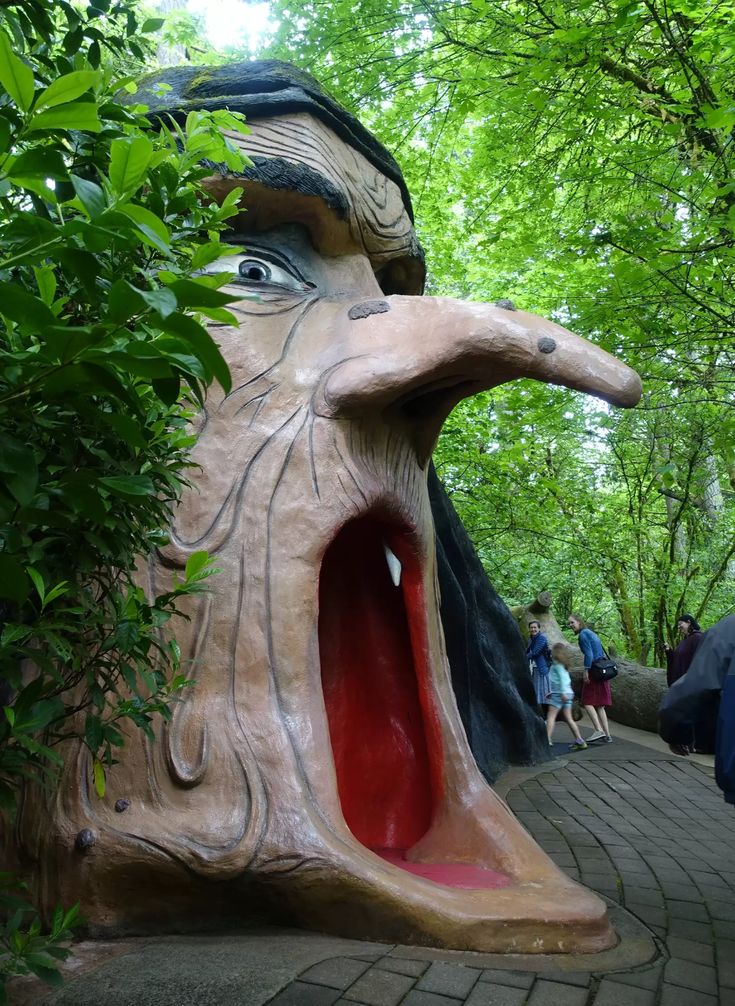 people are walking around in the woods near a sculpture that looks like a cat's head