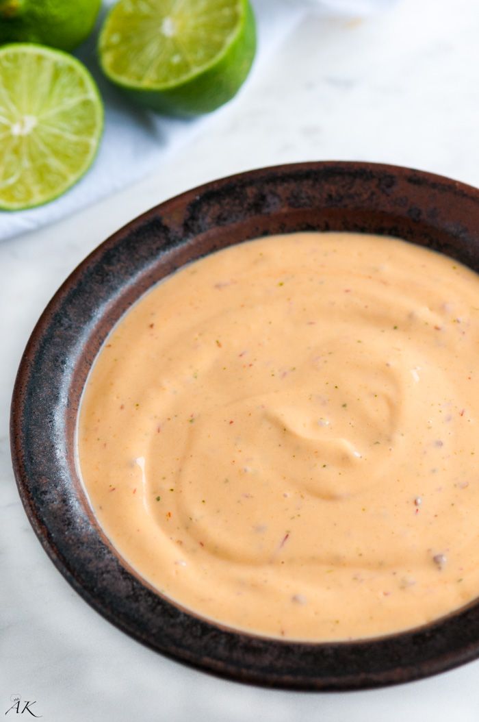 a bowl filled with sauce next to sliced limes