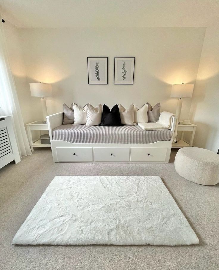 a living room filled with white furniture and pillows on top of carpeted flooring