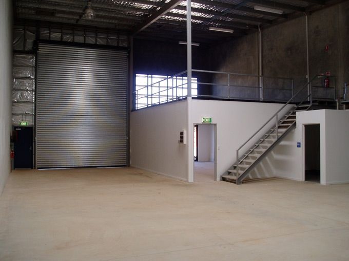 an empty warehouse with stairs leading up to the second floor and storage doors on either side