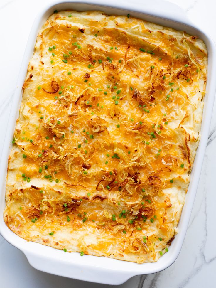 a casserole dish with cheese and onions in it on a marble countertop