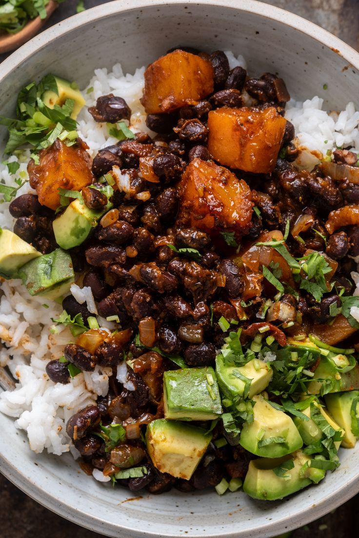 a bowl filled with rice, beans and avocado on top of a table