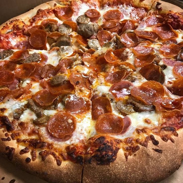 a pepperoni pizza sitting on top of a wooden cutting board in a cardboard box