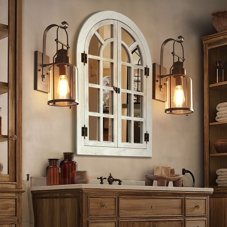 a bathroom with an arched window and wooden cabinetry, along with two lights on the wall