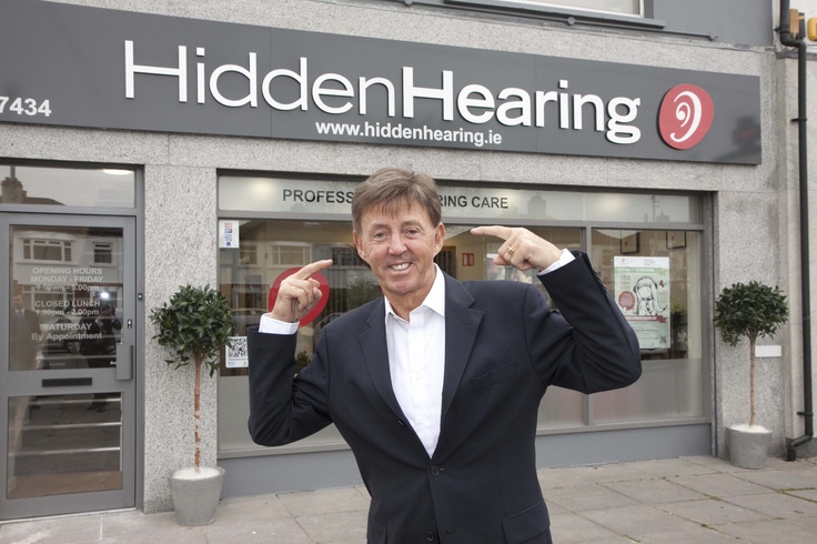 a man standing in front of a building pointing to the side with his fingers up