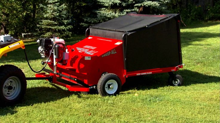 a small red trailer with a black cover on the back is parked next to a yellow tractor