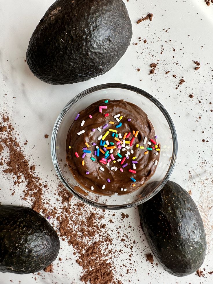 an avocado with chocolate frosting and sprinkles next to it