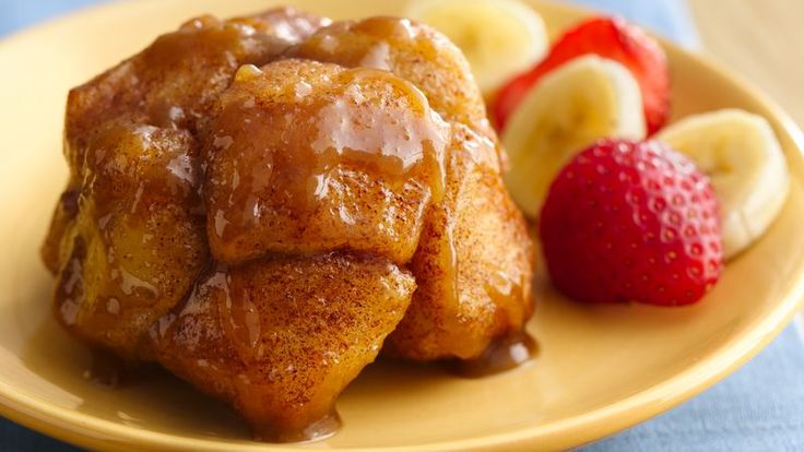 some bananas and strawberries are on a yellow plate with caramel syrup drizzled over them