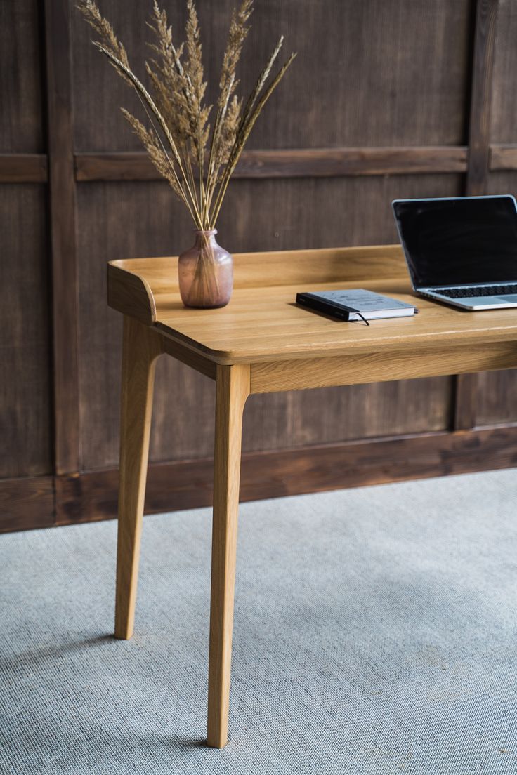 a wooden table with a laptop on top of it next to a potted plant