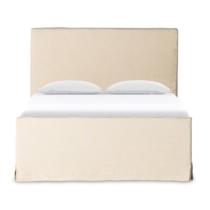 an upholstered bed with white sheets and pillows