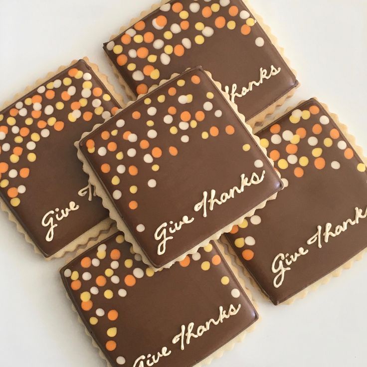 four decorated cookies with the words give thanks written in white lettering on them, sitting next to each other