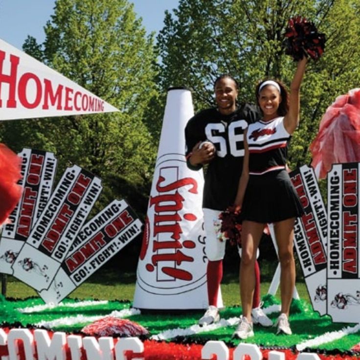 two cheerleaders standing in front of giant candy canes at a college football game