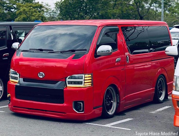 a red van parked in a parking lot next to other cars