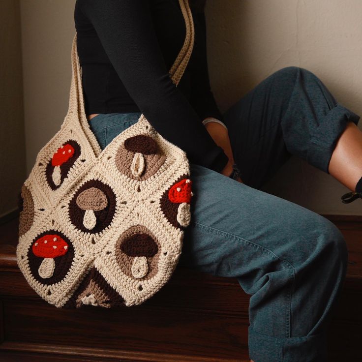 a woman is sitting on the stairs holding a crocheted purse