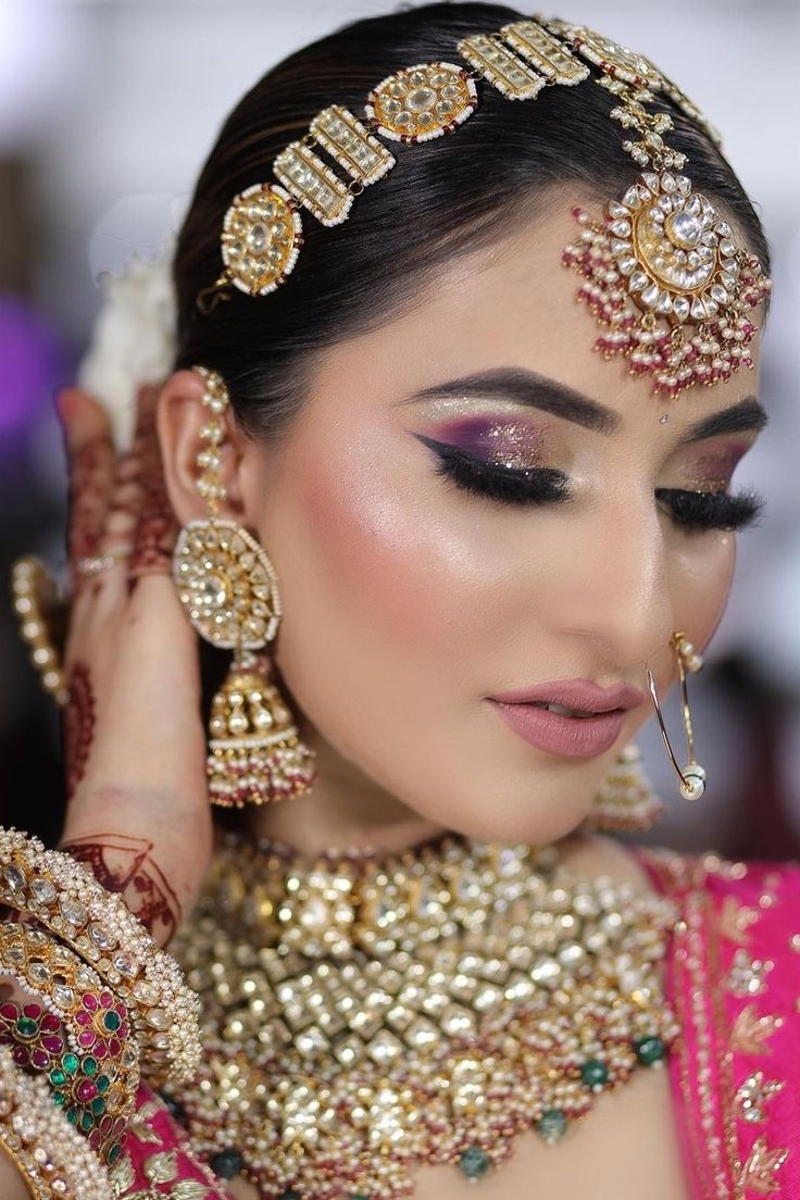 a woman in a bridal outfit with jewelry on her neck and hands behind her head