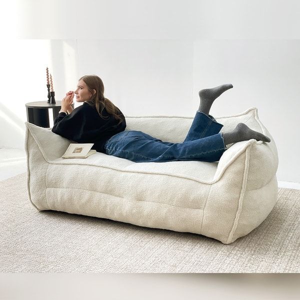 a woman laying on top of a white bean bag chair