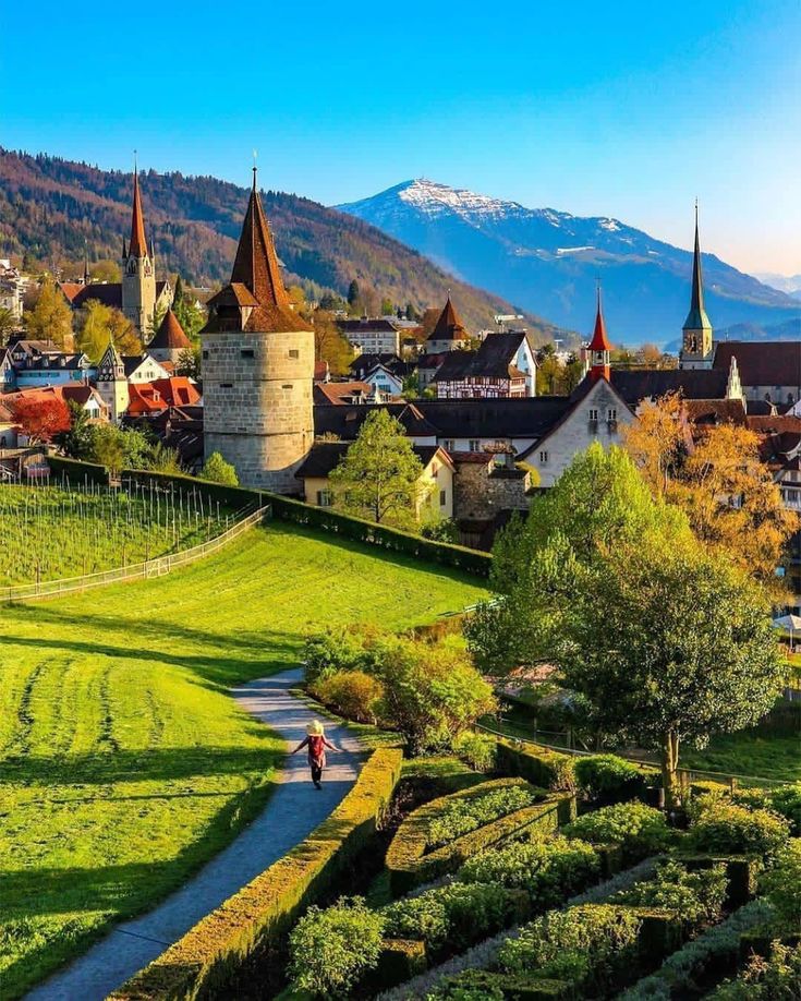 a scenic view of a small town with mountains in the back ground and trees on either side