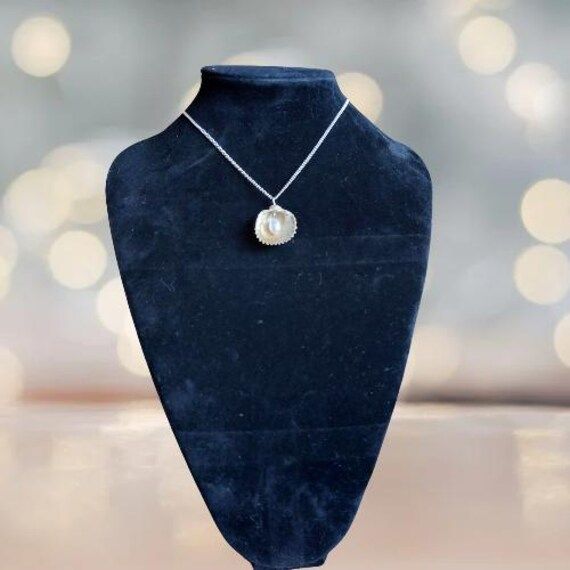 Embrace the beauty of the ocean with our handcrafted Seaside Elegance necklace, a stunning piece that captures the essence of the shore. This necklace features a natural seashell pendant, carefully selected for its unique shape and intricate patterns, paired with a lustrous freshwater pearl that adds a touch of elegance. Each necklace is lovingly handcrafted, ensuring that no two pieces are exactly alike--just like the treasures you find on the beach. The combination of organic elements and time Ocean-inspired Shell-shaped Mother Of Pearl Jewelry, Ocean-inspired Pearl Charm Jewelry For Gifts, Ocean-inspired Pearl Charm Jewelry As Gift, Ocean-inspired Pearl Pendant Jewelry, Ocean-inspired Pearl Charm Jewelry Gift, Ocean-inspired Shell-shaped Pearl Pendant Jewelry, Shell-shaped Pearl Pendant Jewelry, Shell-shaped Jewelry With Pearl Pendant, Ocean-inspired Mother Of Pearl Shell Necklace As Gift