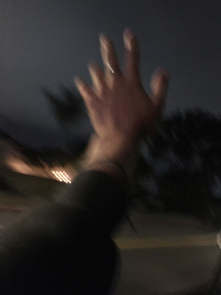 a blurry photo of someone's hand reaching out to catch something in the air