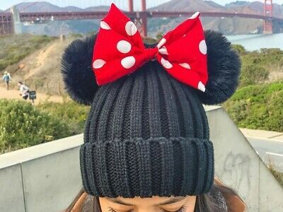 a woman wearing a minnie mouse hat with a red bow on it's head