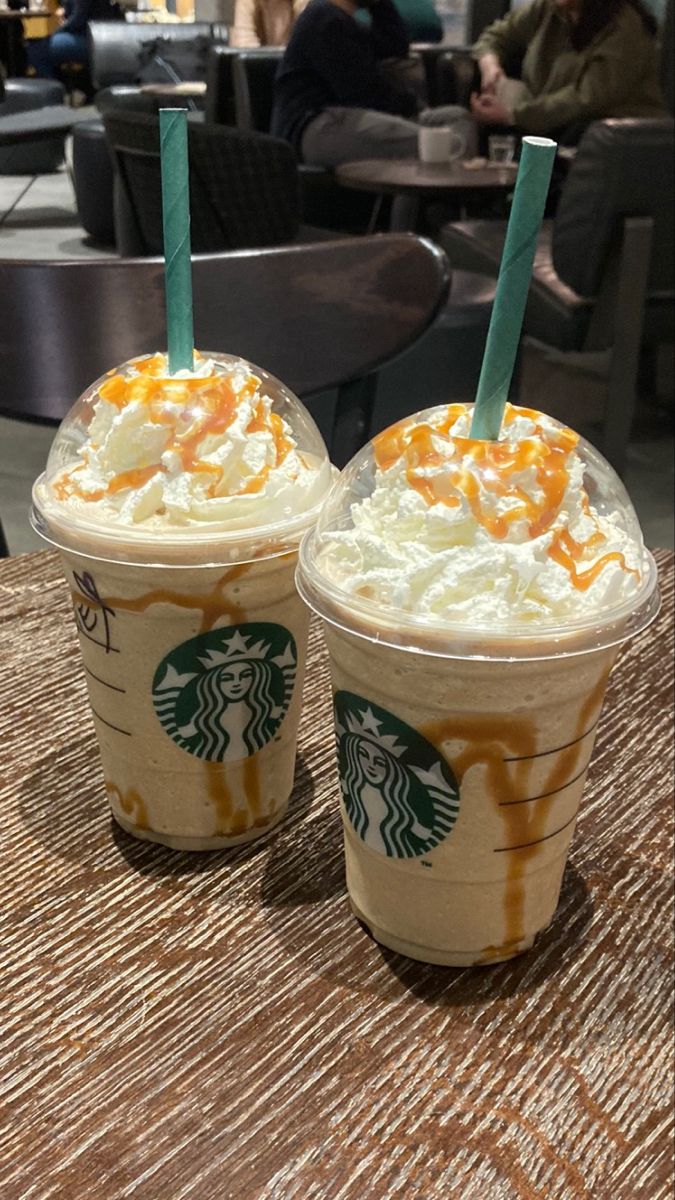 two starbucks drinks sitting on top of a table