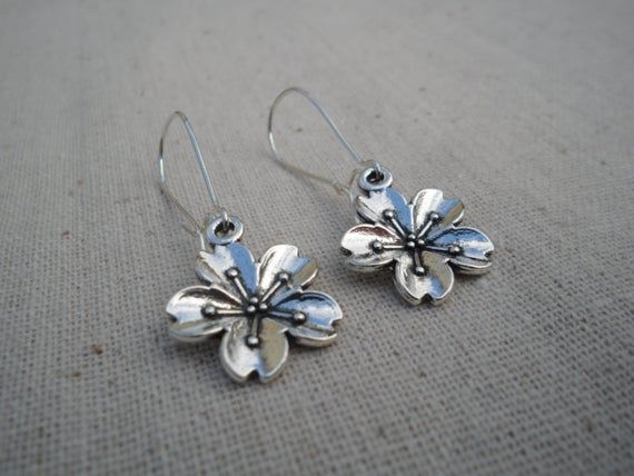 These are unique and beautiful cherry blossom flower earrings.  They are happy and fun.  The charms measure about 5/8" across as well as up and down.  The dangle and dance from 1" long kidney style earwires.  Made from allergy free plated silver.  The over all drop of the earrings is about 1 5/8" long.These are perfect for everyday, year round wear and would also make a very nice gift.Tiger Flower Jewelry - Inspired by Nature Blossom Flower Charm Earrings For Spring, Blossom Colored Flower Charm Earrings For Spring, Blossom Color Earrings With Flower Charm For Spring, Blossom Color Flower Charm Earrings For Spring, Silver Flower Earrings For Spring Gift, Spring Flower Dangle Earrings Gift, Spring Sterling Silver Earrings With Flower Charm, Whimsical Spring Flower Earrings With Ear Wire, Whimsical Earrings For Spring Gift