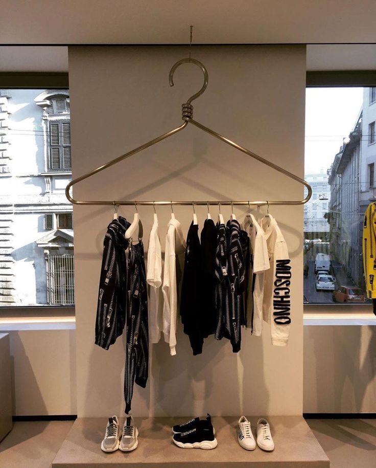 clothes are hanging on a rail in front of a window and shoes hang from the rails