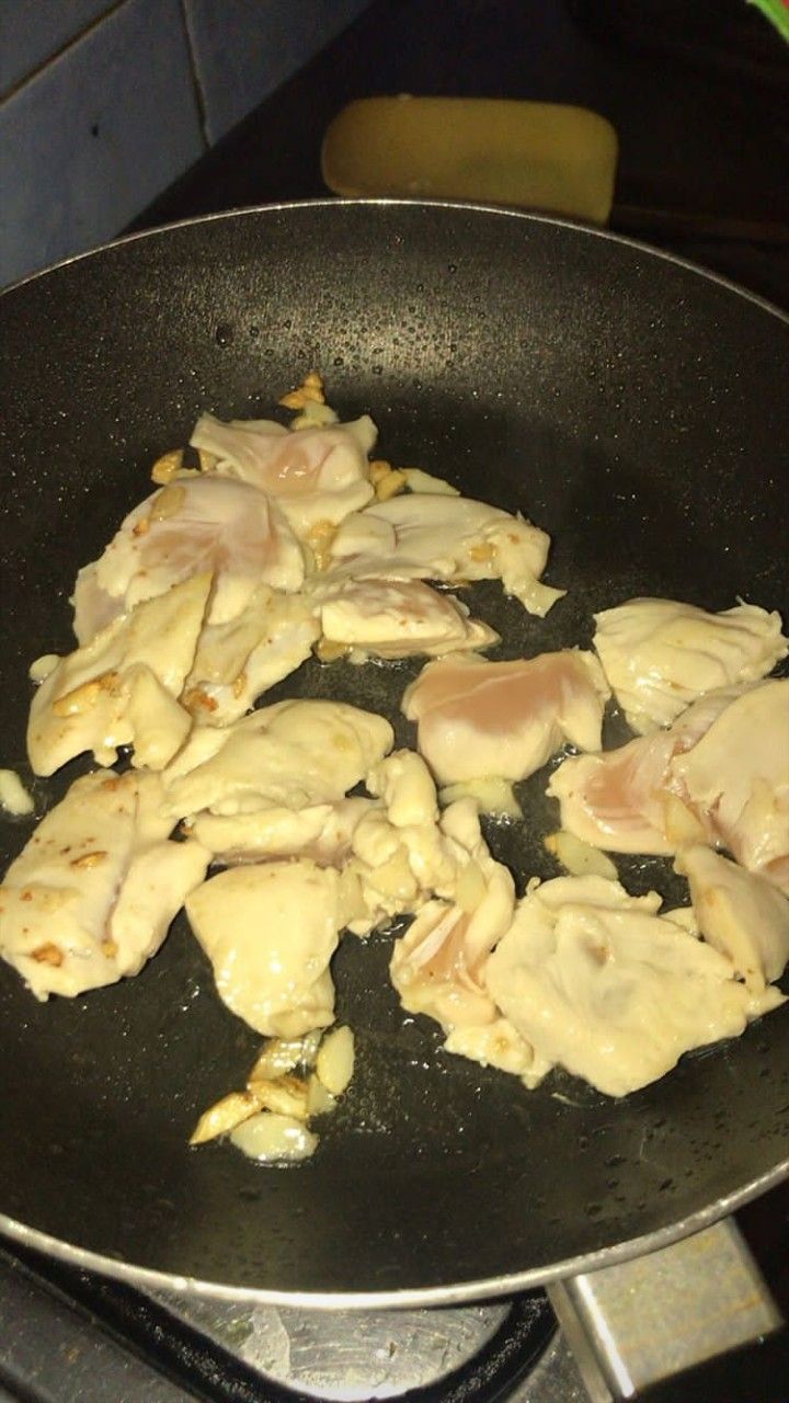 chicken cooking in a frying pan on the stove