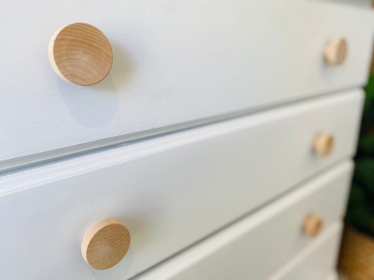 a white dresser with wooden knobs on it