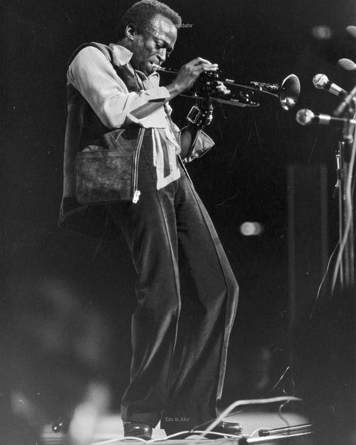 a black and white photo of a man playing the trumpet in front of microphones