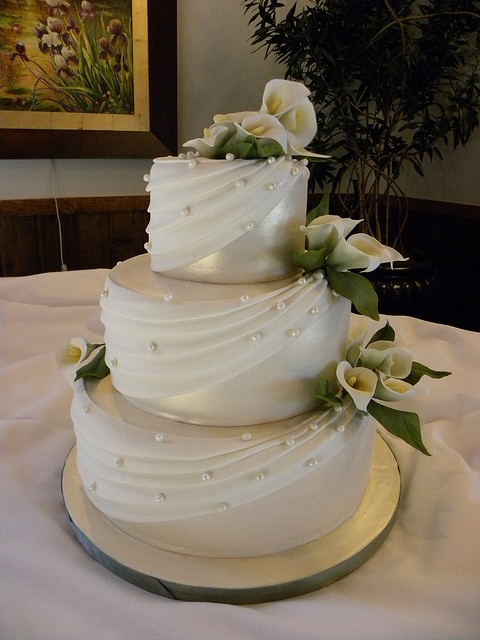 a three tiered white wedding cake with flowers on top