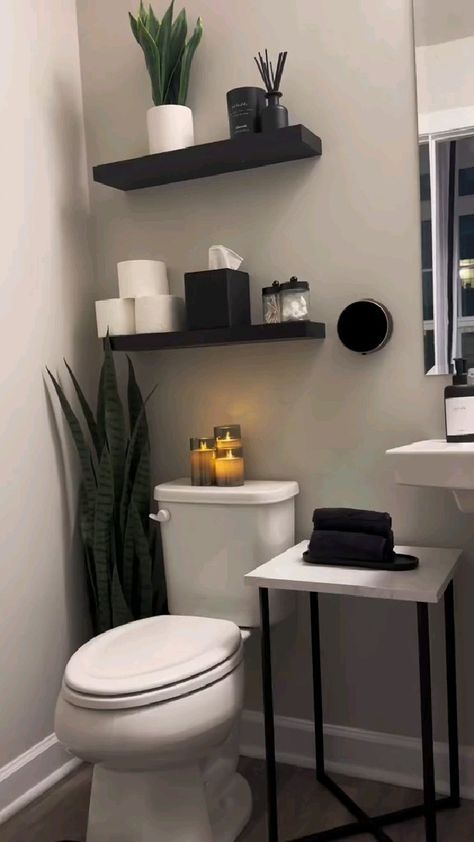 a white toilet sitting in a bathroom next to a sink and a mirror with candles on it