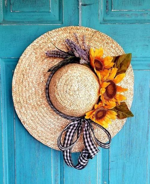 a straw hat with sunflowers tied to it on a blue front door frame