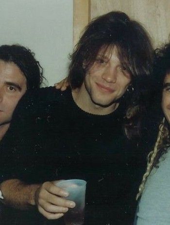 two men and a woman are posing for a photo with one man holding a cup