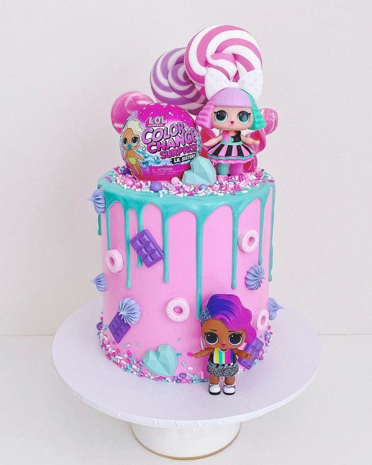 a pink and blue cake decorated with lollipops, candy, marshmallows and candies