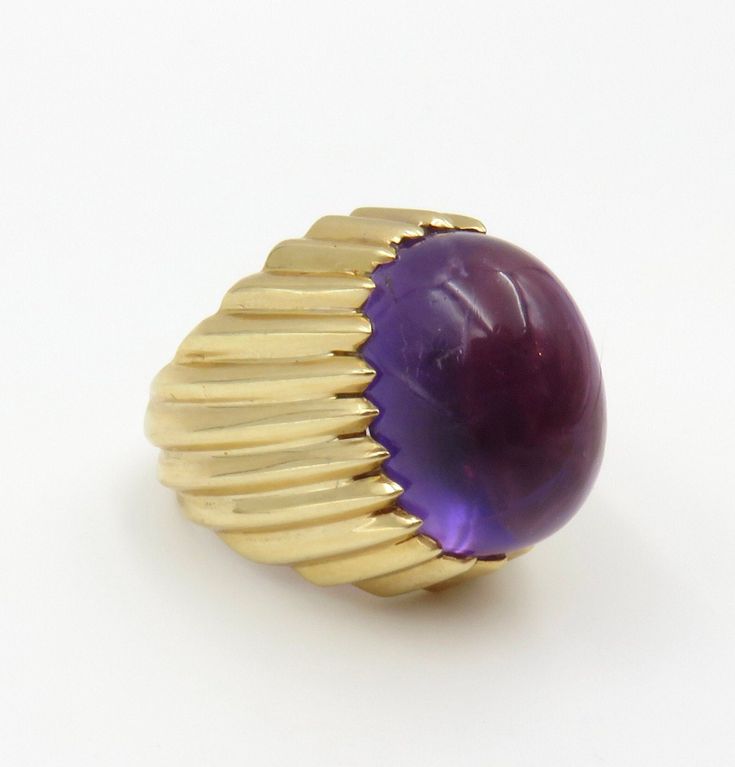 "Circa 1970's.  Gorgeous and bold 14KT gold ring featuring a 16.12 carat oval cabochon Amethyst.  The grooved setting design integrates seamlessly at the top into a sawtooth bezel setting. The Amethyst stone has a purple hue and a medium dark/ moderately strong tone and saturation.  Really beautiful. Certainly a stunning statement ring or, also known as a cocktail ring.  Either description suits this ring to a \"T\"  It is approximately a size 8 and can be sized.  SIZING:  The majority of my rin Purple Hues, Amethyst Stone, Oval Cabochon, Amethyst Ring, Cocktail Ring, 14kt Gold, Cocktail Rings, Bezel Setting, Statement Ring