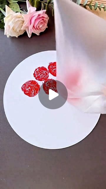 a white plate topped with red roses on top of a table next to pink flowers