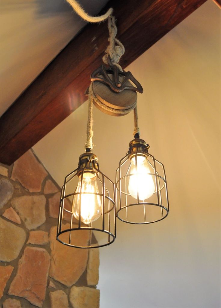 two light fixtures hanging from the ceiling in a room with stone walls and wood beams