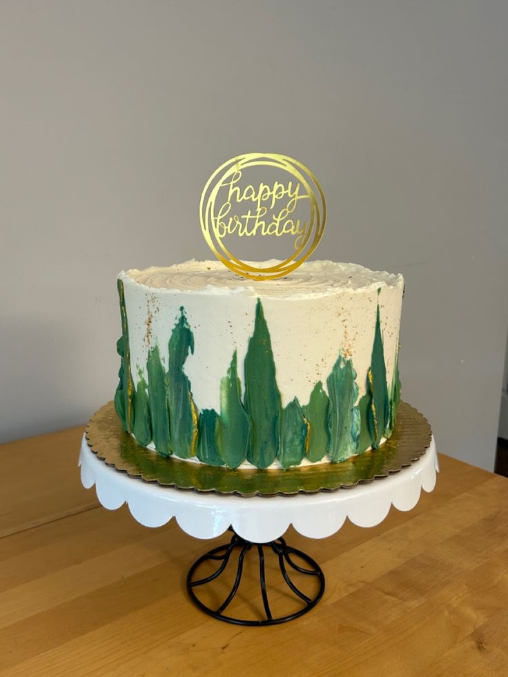 a white and green birthday cake on a wooden table