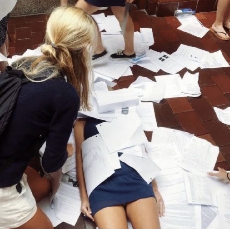 a group of women sitting on the ground with lots of papers scattered all over them