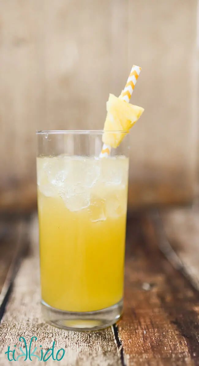 a glass filled with yellow liquid and a straw sticking out of it's top