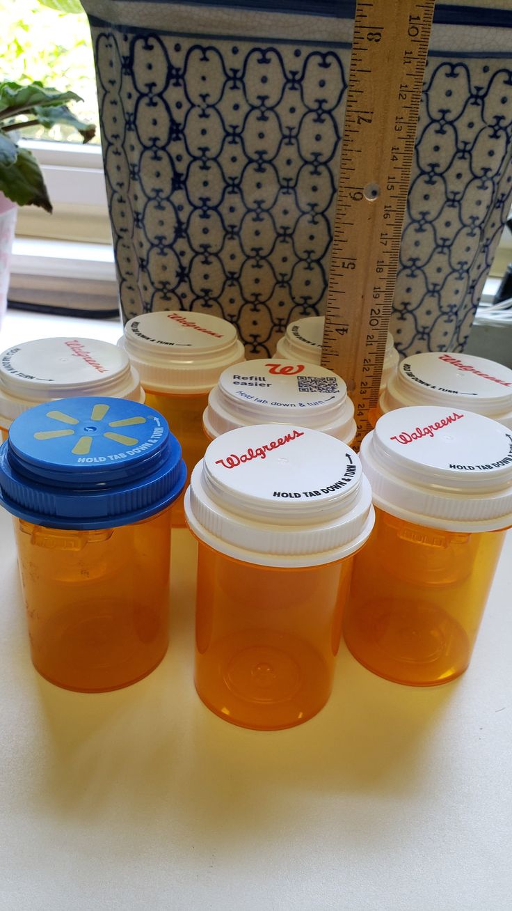 four jars of honey sit on a table next to a ruler